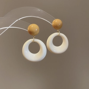 Detail of minimalist resin hoop earrings featuring yellow beads on a transparent stand
