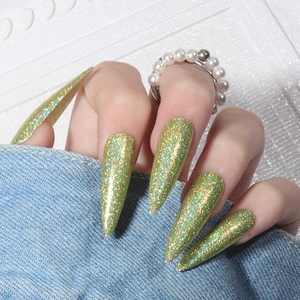 Macro detail of long stiletto green holographic laser glitter nails worn by a model