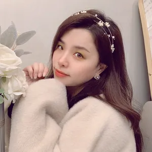 Dettaglio del cerchietto con perle e orecchini floreali su modella per un look elegante
