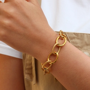 Close-up of a chunky gold chain bracelet on a model's wrist with textured links