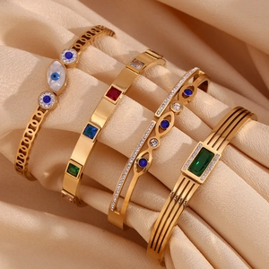 Detail of 18K gold-plated stainless steel bracelets with evil eye and colored zircons