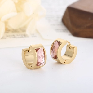 Macro shot of gold-plated hinged earrings featuring a faceted pink square crystal inlay