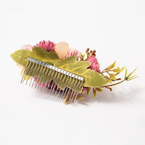 Detail of pink and burgundy fabric flower hair comb with green leaves and silver metal teeth