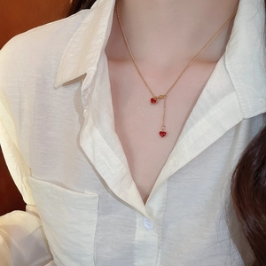 Detail of a gold necklace featuring two red heart pendants on a model's collarbone