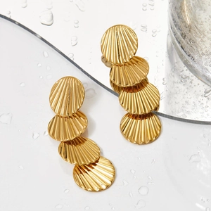 Long gold shell drop earrings with radial stripes on a reflective water surface