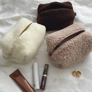 Kosmetiktaschen aus Lammwolle in Creme, Braun und Beige auf weißem Stoffhintergrund