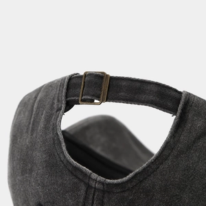 Close-up of washed black cotton baseball cap with adjustable bronze metal buckle strap