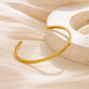 Detail of 18k gold plated stainless steel cuff bangle with circular zircon inlay on silk