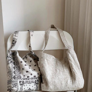 Détail de sacs fourre-tout brodés avec motifs paisley et texture plissée sur une chaise