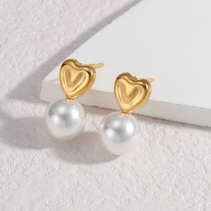 Detail showing heart-shaped gold studs with round white pearls on a textured background