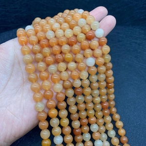 Close-up of natural red aventurine round stone beads held in hand for DIY jewelry making