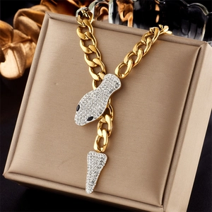 Detail of a gold-tone snake pendant featuring white crystals and black eyes on a box