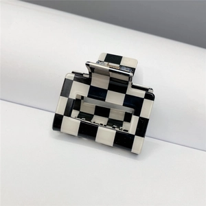 Close-up of a large black and white checkerboard hair claw clip with a glossy finish