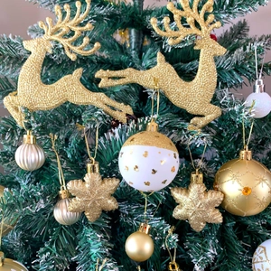 Dettaglio di renne dorate glitterate e fiocchi di neve su un albero di Natale festoso