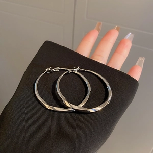 Polished silver twisted hoop earrings with large asymmetrical metal design for women