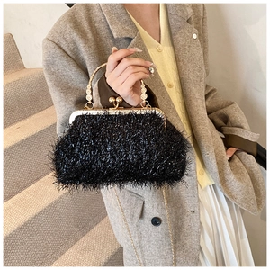 Detail of black feather evening clutch bag with sparkling rhinestone gold handle