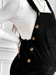 Detail of black corduroy maternity overall dress with buttons and adjustable drawstrings