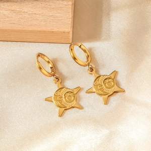 Gold stainless steel hoop earrings with sun and star pendants on a wooden background