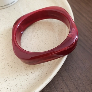 Detailed macro view of a deep red marble textured acrylic bangle on a ceramic plate