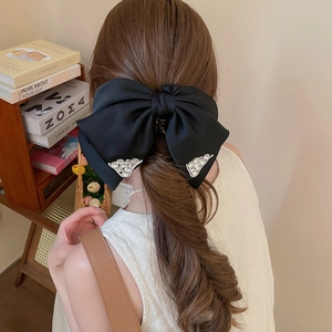 Close-up of a large black satin bow hair claw clip with silver rhinestone accents