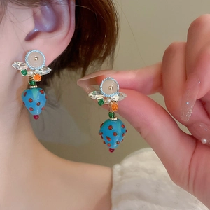 Blue resin strawberry earrings with crystal accents and woven details on a model