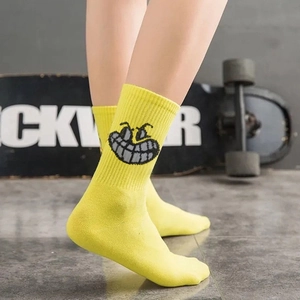 Detail of yellow mid-calf socks with a cartoon smiley face and skateboard street style