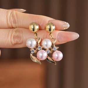 Gros plan détaillé de boucles d'oreilles fleuries dorées avec perles blanches et roses