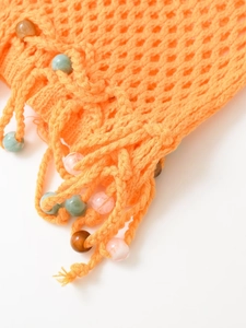 Detail of orange crochet texture with colorful beads and matching fringed tassels