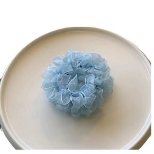 Blue ruffled mesh scrunchie in candy colors on white tray with minimalist aesthetic
