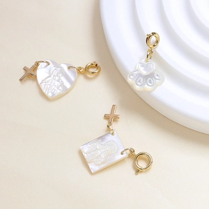 Macro detail of gold-plated mother of pearl pendants with heart and cat paw religious motifs