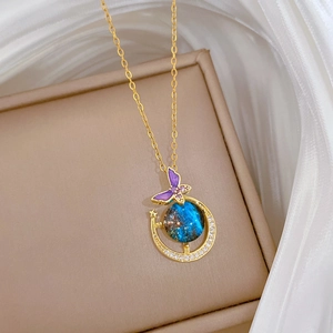 Golden necklace with purple butterfly and blue planet pendant on silk background