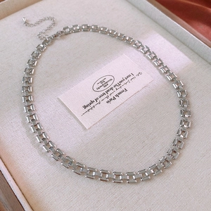 Detail view of silver square link chain necklace displayed on beige fabric jewelry box