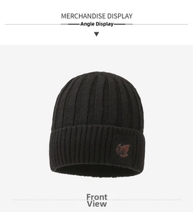 Close-up of black ribbed knit beanie featuring a brown brand label and soft winter texture