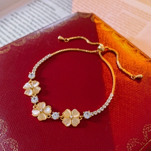 Detail of flower bracelet with cat eye stones and zircons on red luxury background