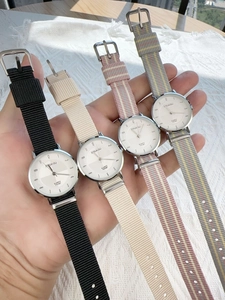 Close-up of minimalist quartz watches with colorful nylon canvas straps on a wrist