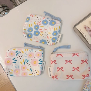 Flat lay of three floral cotton mini pouches with zipper and simple wish woven label