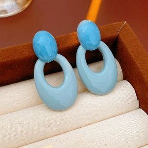 Macro shot of blue oval resin earrings nestled in a premium jewelry display box