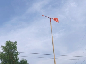 Ripresa dal basso di una banderuola rossa con freccia e coda su uno sfondo di cielo nuvoloso