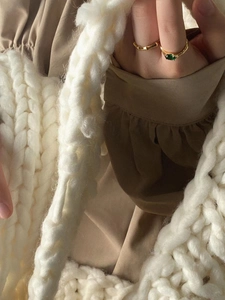 Detailed view of 925 silver ring with green ruby stone against a knitted bag background