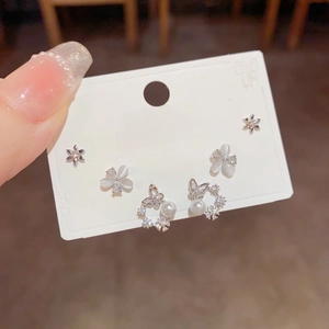 Detail of silver S925 earrings set with zircon flower, butterfly and pearl charms