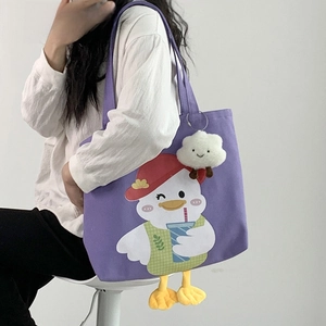 Detail of purple canvas tote bag featuring a cute cartoon duck and plush cloud pendant