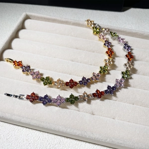 Detail of four-leaf clover bracelets in gold and silver with rainbow zircon inlay on tray