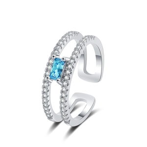 Double-layered silver ring with pavé stones and emerald-cut blue gemstone on white background