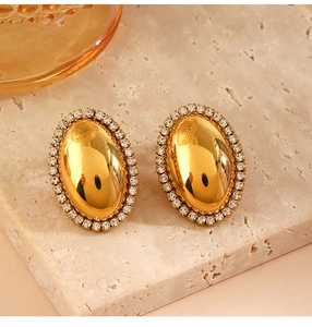 Detail of vintage gold oval stud earrings with sparkling zircon inlay on stone base