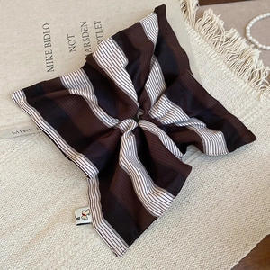 Detailed shot of brown and white striped fabric scrunchie with elegant pearl accessories