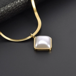 Macro view of gold snake chain with a white shell pendant on dark texture