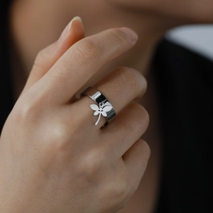 Close-up of model wearing a wide silver stainless steel ring with a dragonfly charm