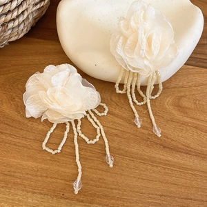Close-up of chiffon flower earrings with crystal tassels on a rustic wood background