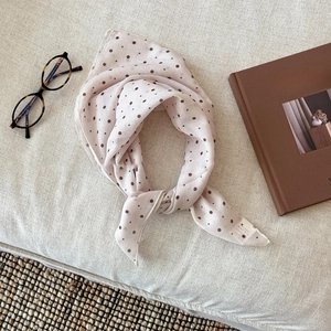 Close-up of beige polka dot cotton linen scarf with rolled edges and wash care label