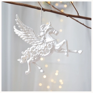 Close-up of a white resin Pegasus Christmas ornament with glitter wings on a tree